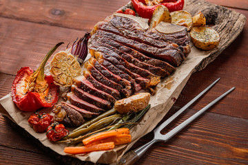 marbled beef steak on the bone cooked to a state of medium rare grill. next to the steak, grilled vegetables serving as a side dish. lovely gala dinner for two