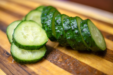 Slices of fresh cucumber on a wooden cutting Board close up.