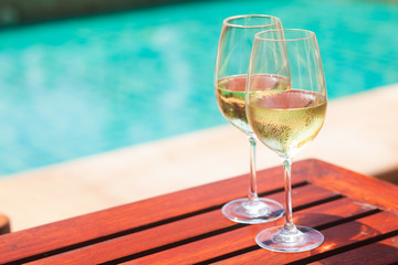 Elegant flute glass of sparkling white wine or champagne by side of swimming pool
