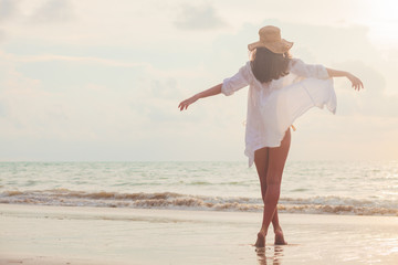 carefree woman in straw hat walking in the sunset on the beach. vacation vitality healthy living concept