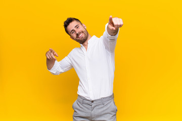 young handosme man feeling happy and confident, pointing to camera with both hands and laughing,...