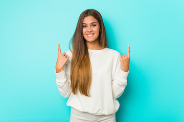 Young slim woman indicates with both fore fingers up showing a blank space.