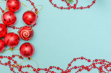 Red Christmas beads with red balls on light blue background. Christmas frame. The view from the top. Copy space