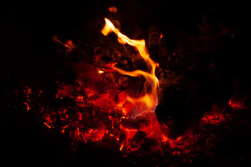Fiery red coals in dying bonfire at dark night.