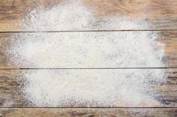 White flour on a wooden background, top view. Background with copy space