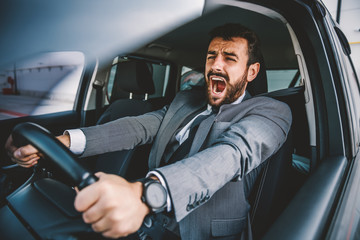 Frightened handsome caucasian businessman screaming while sitting in car and having car accident.
