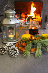 Obraz na płótnie Canvas in the furnace the fire burns, a candlestick and a fir-tree, the new year's atmosphere, the burning hearth in the house, selective focus,wine is poured in a glass