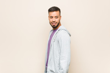 Young south-asian man looks aside smiling, cheerful and pleasant.
