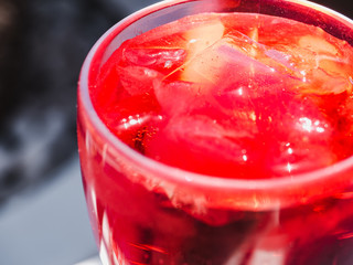 Beautiful wineglass with a pink cocktail and ice cubes, standing on a white board against the...