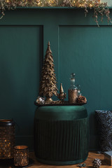Christmas composition on the green velvet pouf in living room. Beautiful decoration. Christmas trees, candles, stars, lights and elegant accessories. Merry Christmas and Happy Holidays, Template. 