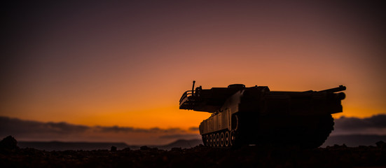War Concept. Armored vehicle silhouette fighting scene on war fog sky background. American tank at...