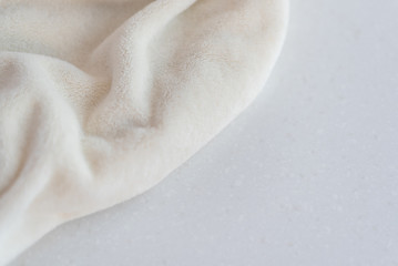 Soft cozy plush fabric with pile lies in beautiful folds on white marble countertop background....