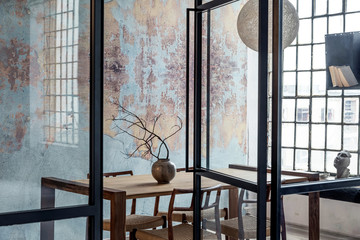 Stylish interior design of dining room in loft apartment with wooden sharing table, chairs,flowers...