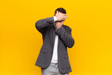 young handosme man covering face with both hands saying no to the camera! refusing pictures or...