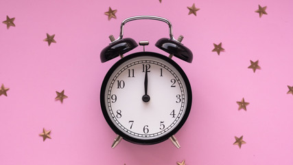 New Year Christmas Top view flat lay black alarm clock twelve covered golden stars confetti copy space millennial pink color paper background minimal style Template feminine blog social media postcard