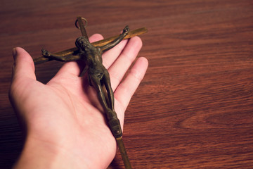 hand holding christ gold cross with wood background, christian and peace hope religion concept