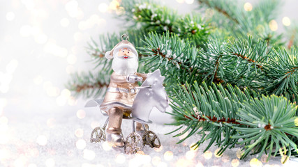 Christmas and New Year decorative greetind card. Bauble of Santa Claus and natural branch of blue fir on the white snow background.