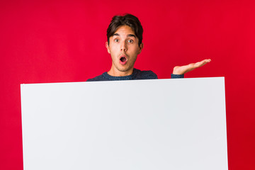 Young man holding a placard impressed holding copy space on palm.