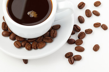 White coffee cup on saucer and roasted beans isolated on white background. Full depth of field. Close up.