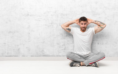 young handosme man feeling stressed, worried, anxious or scared, with hands on head, panicking at...