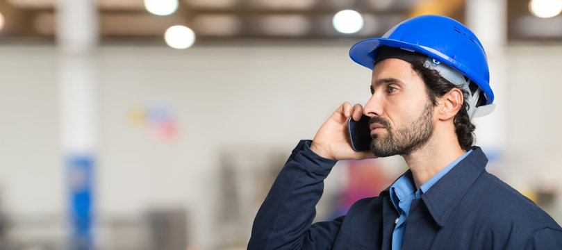 Mechanical worker talking on the phone in a factory