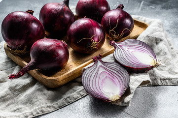 Red onion in a wooden bowl, onion halves. Farm organic vegetables. Gray background. Top view