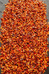 Close up view of red chili flakes on black slate background. Crushed red cayenne pepper. 