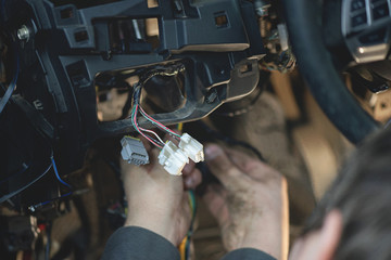 Auto electrician is working with car wiring close up.