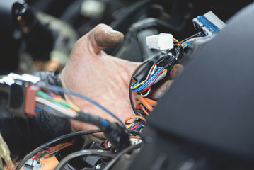 Auto electrician is working with car wiring close up.