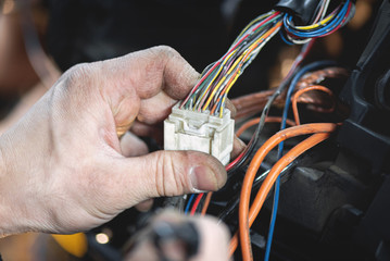Auto electrician is working with car wiring close up.
