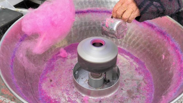 M&aacute;quina de algod&oacute;n trabajando y mano rellenado az&uacute;car azul