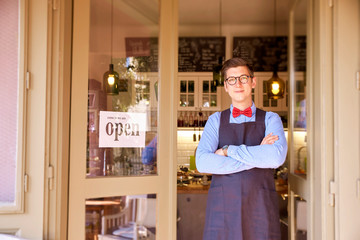 Portrait shot of small business owner young man standing in his small cafe with arms crossed