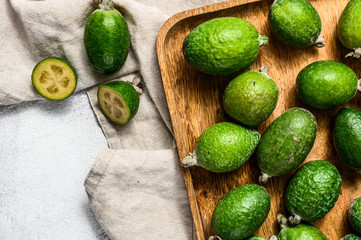 Green feijoa fruits in a wooden plate on a grey background. Tropical fruit feijoa. Top view.