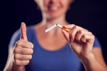 Woman holding broken cigarette in hands. Stop smoking concept