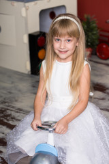 Cute girl is playing with toy cars. Rides a toy typewriter airplane. Happy childhood.