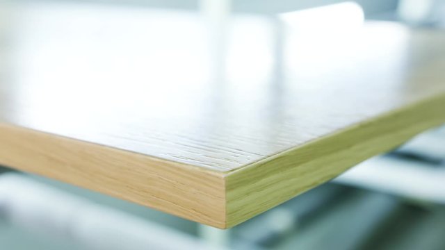 Close-up of large polished wooden board lying on the table at the wooden workshop or factory. Action. Production, manufacture and woodworking industry concept