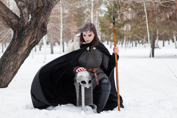  The girl is a warrior of the Viking era in a chain mail coat and fur with a spear in his hands....
