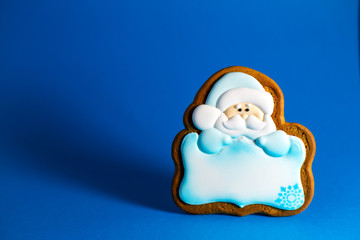 gingerbread cookie of Santa's with copyspace on blue background. Traditional Christmas food. Christmas and New Year holiday concept.