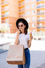 Attractive girl walking with ice cream holding shopping bags in shopping mall
