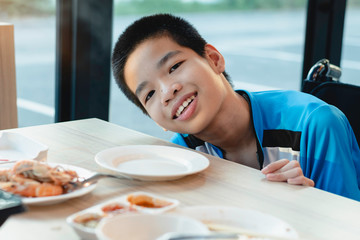 Disabled child on wheelchair eating Shabu, His favorite Asian food, Restaurant background, Special...