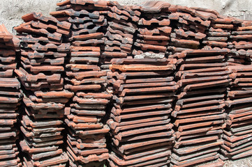 Stack of old used red terracotta Mediterranean ceramic roof tiles closeup
