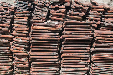Stack of old used red terracotta Mediterranean ceramic roof tiles closeup