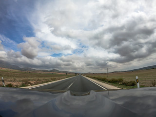 pov driving a car on asphalt road in Andalusia.A power line cross the lane.