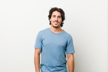 Fototapeta premium Young handsome man against a white background happy, smiling and cheerful.