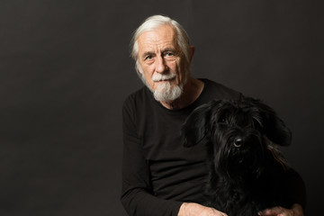 Low key studio portrait of old man and his dog