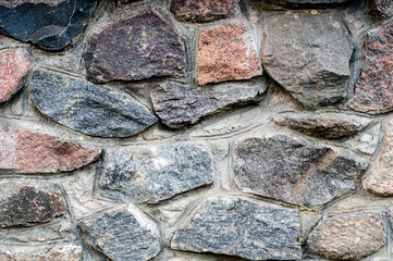 Background in the form of a fragment of a stone wall with textured stones from a colored rubble.