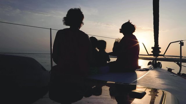 Mother and grandmother with children on a sailboat watching the sunset
