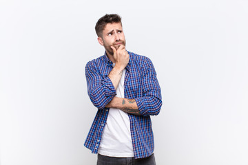 young handosme man thinking, feeling doubtful and confused, with different options, wondering which...