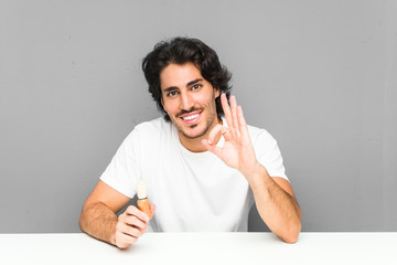 Young man shaving his beard cheerful and confident showing ok gesture.