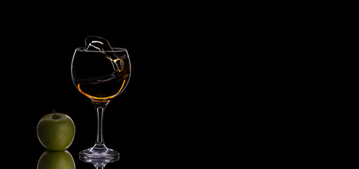 Close-up of glass with whiskey with green apple on a dark background with copy space. Dark mode. Food photo for banner. Zero gravity. Concept sales, discount price.